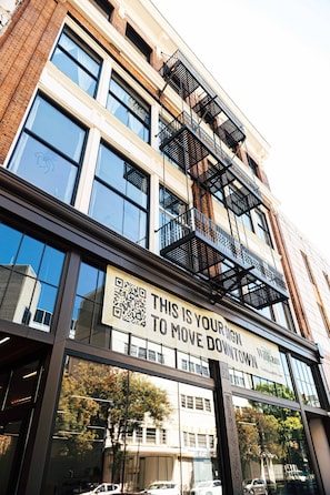A building with large windows, a sign reading 'THIS IS YOUR SIGN TO MOVE DOWNTOWN,' and a QR code.