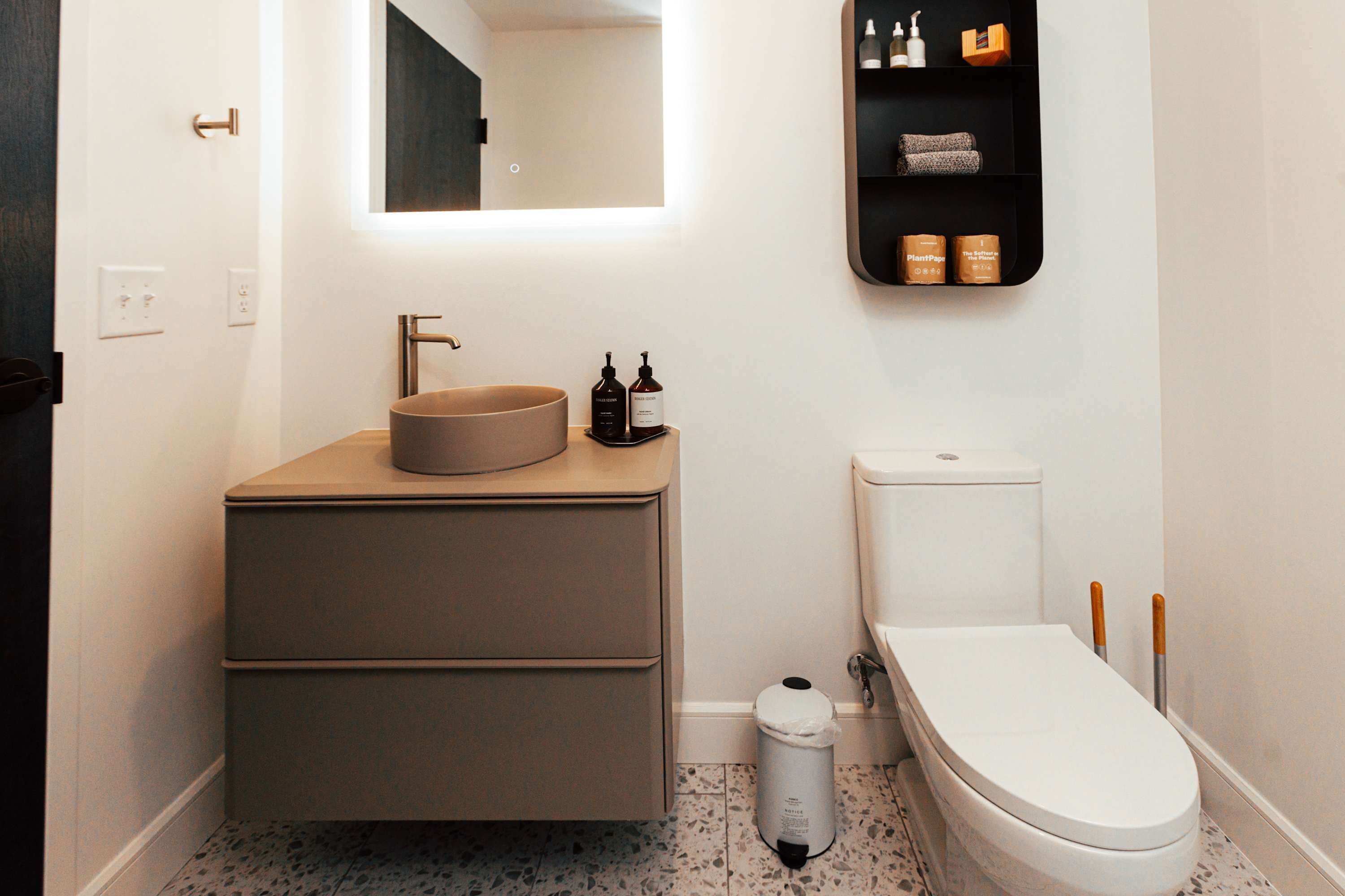 Ein modernes Badezimmer mit einem runden Waschbecken, einer Toilette und einem Spiegel über dem Waschbecken.