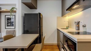A modern kitchen with a black refrigerator, a dining table with chairs, and a built-in oven. - NOK Modern 1BR Near Usaquen Unicentro (Bogotá)