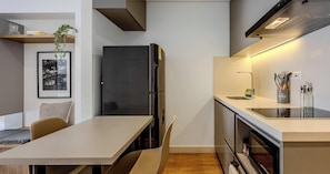 Eine moderne Küche mit einem schwarzen Kühlschrank, einem Esstisch mit Stühlen und einem eingebauten Backofen.