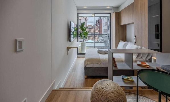 Eine moderne Wohnung mit Balkon, einem Bett, einem Sofa und einem Essbereich.