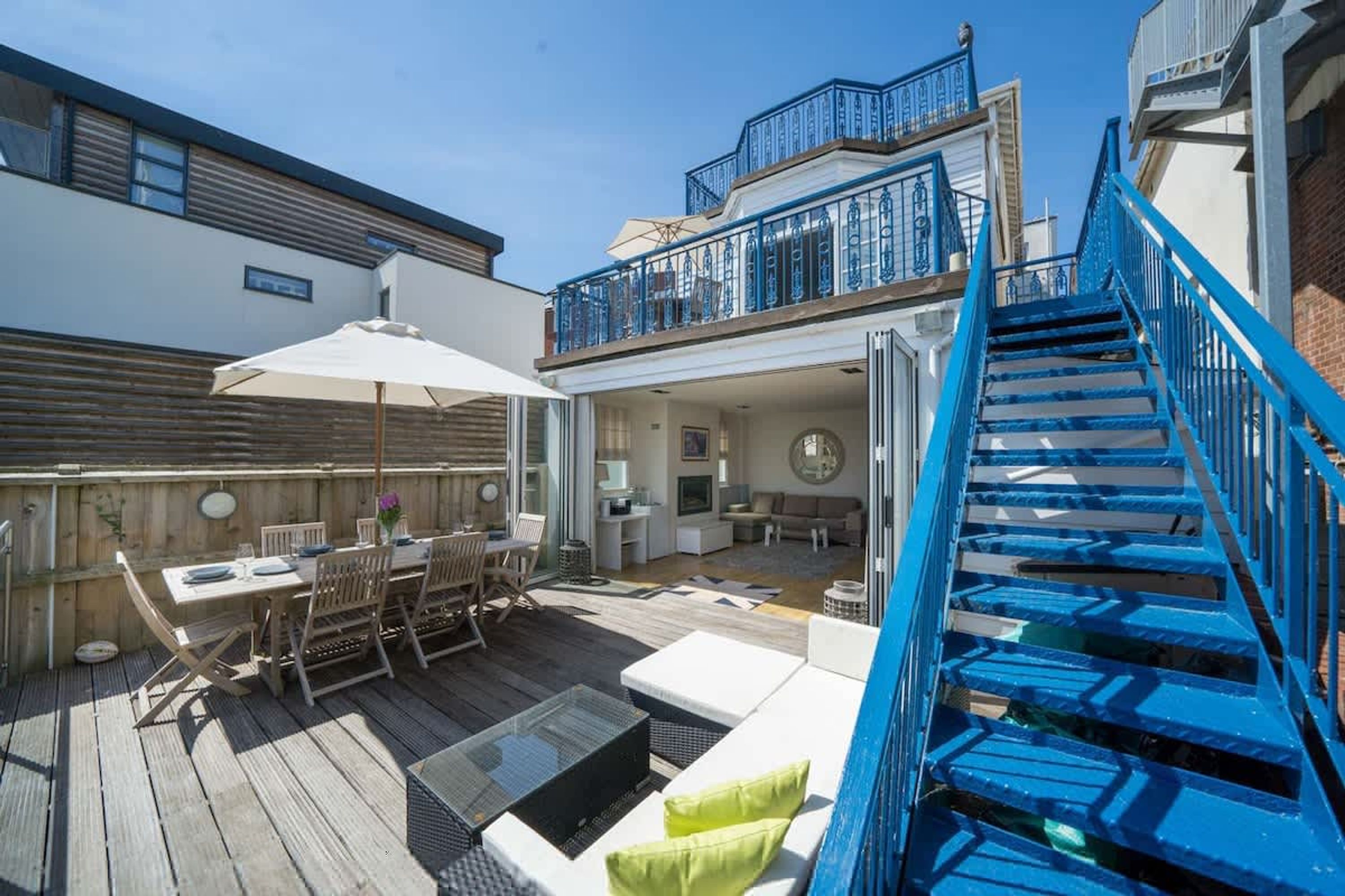 A deck with outdoor furniture, a staircase, and a view of the interior.