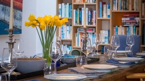 A dining area with a table set for six, surrounded by bookshelves filled with books. - Park View 5 Bedroom Home With Solent Park Views (Cowes)
