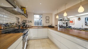 A modern kitchen with a central island, a stove, and a window. - Park View 5 Bedroom Home With Solent Park Views (Cowes)