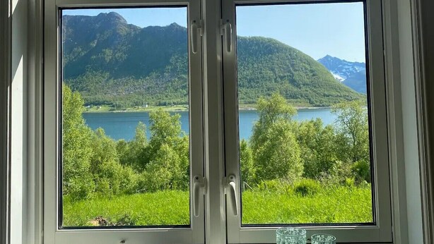 Et vindue med udsigt over en sø og bjerge.