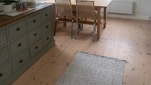 Et køkken med spisebord, stole, en hængende lampe og udsigt gennem vinduet.