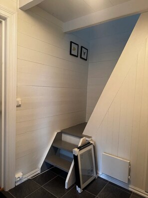 A staircase with white walls and a dark floor, leading to a landing with a framed picture.