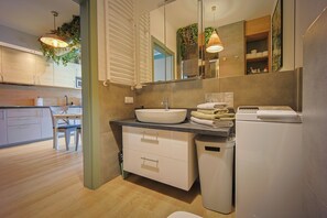 Uma casa de banho moderna com lavatório, espelho e porta-toalhas.