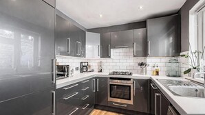 Una cocina moderna con armarios oscuros, horno empotrado y pileta de acero inoxidable.