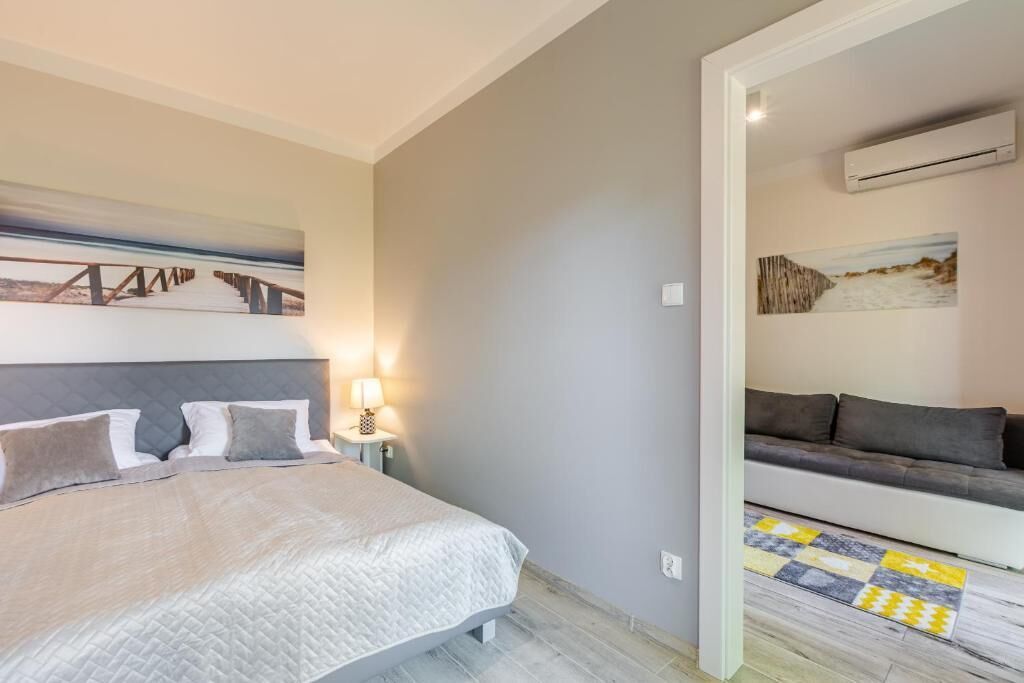 Un dormitorio con cama, lámpara de noche y un cuadro en la pared.