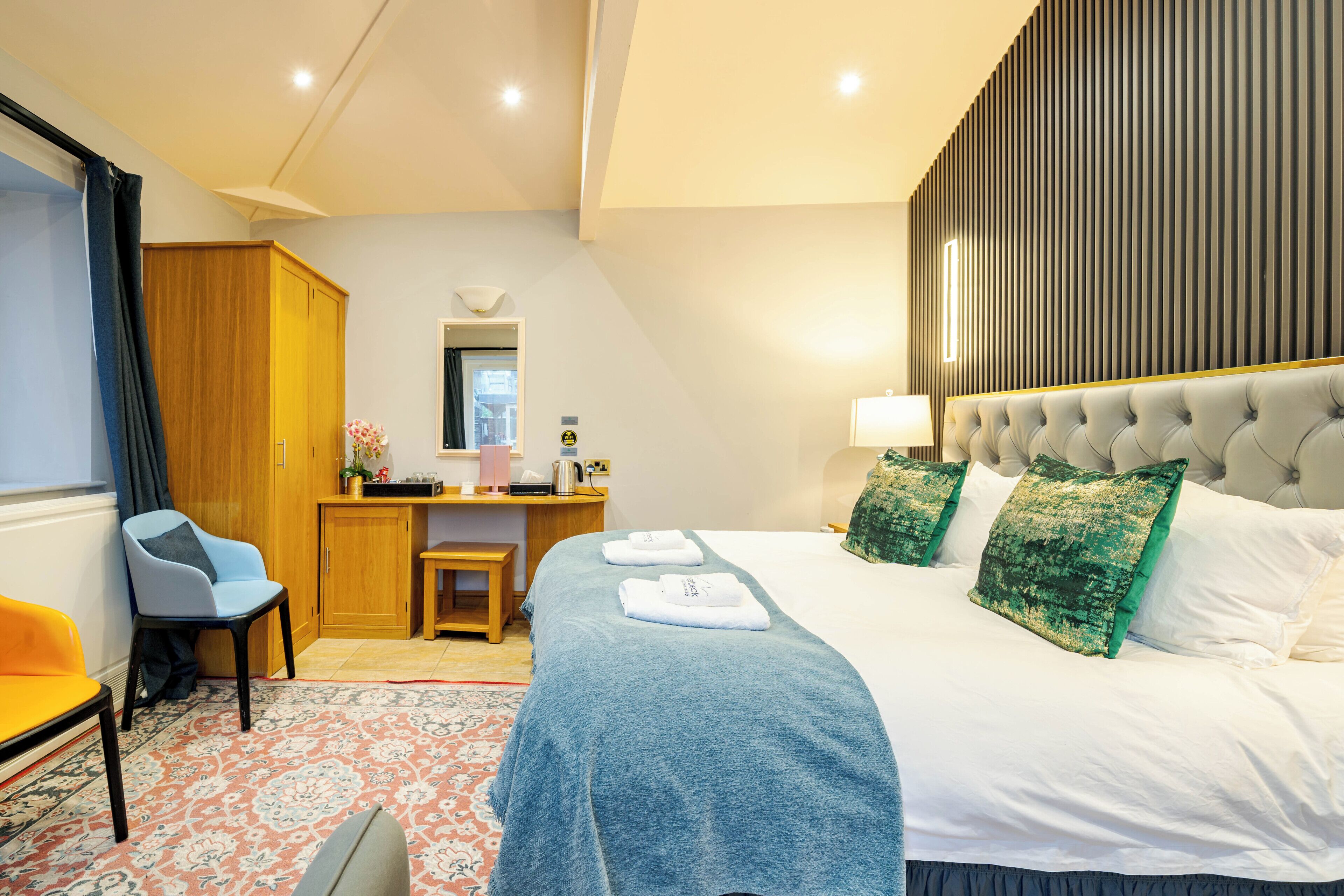 A hotel room with a bed, a desk, a chair, a wardrobe, and a bathroom.