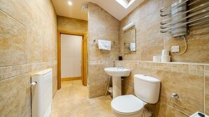 A bathroom with a skylight, a toilet, a sink, and a towel rack. - Waterhead Retreat (Ambleside)