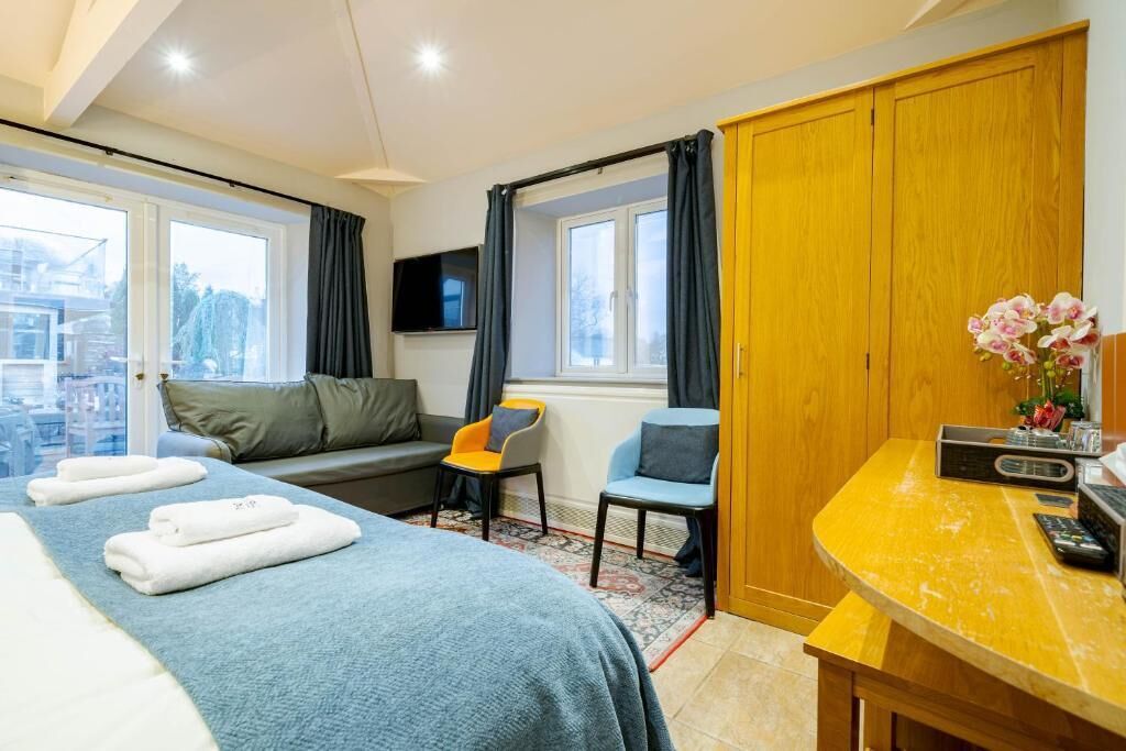 Et hotelværelse med seng, sofa, skrivebord, stol, fjernsyn og skab.