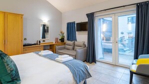 A hotel room with a bed, a desk, a sofa, and a sliding glass door to the outside. - Waterhead Retreat (Ambleside)