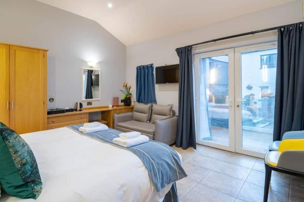 A hotel room with a bed, a desk, a sofa, and a sliding glass door to the outside.