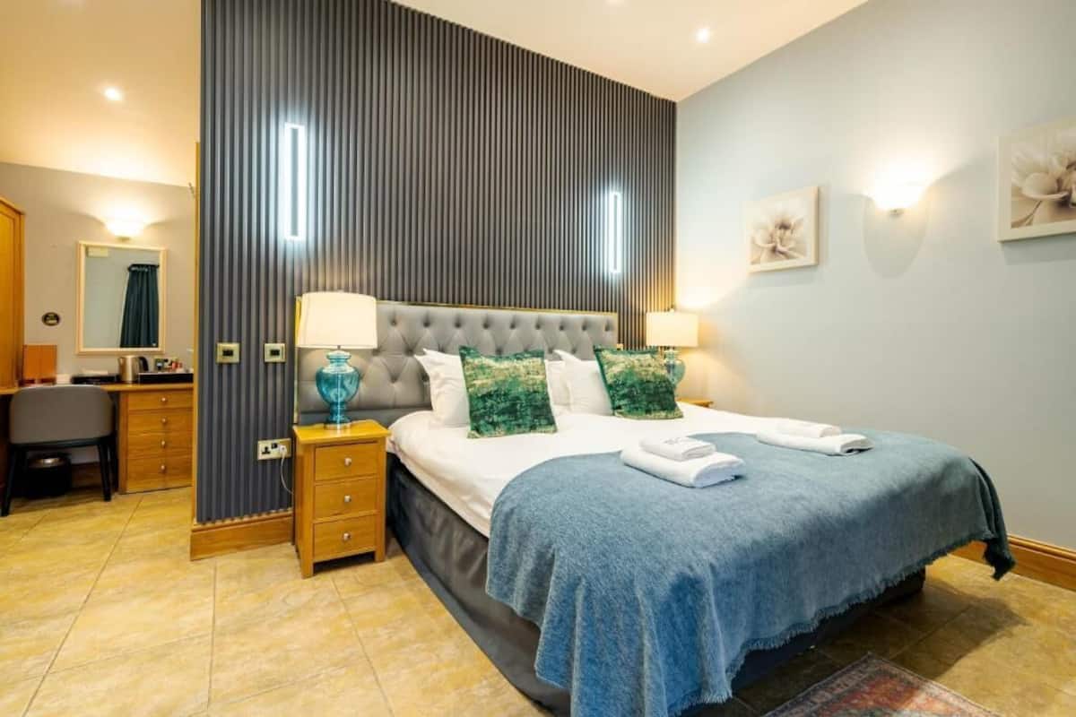 A bedroom with a tufted headboard, a desk, a chair, and a bed with a blue bedspread.