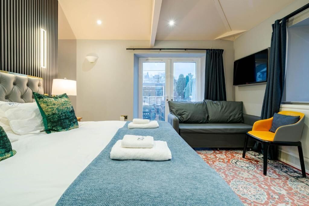 A hotel room with a bed, a sofa, a TV, and a view of the city.