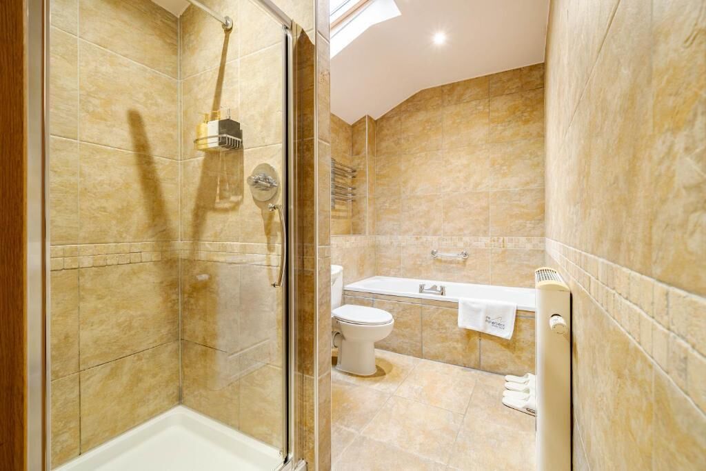A bathroom with a glass-enclosed shower, a toilet, and a bathtub.