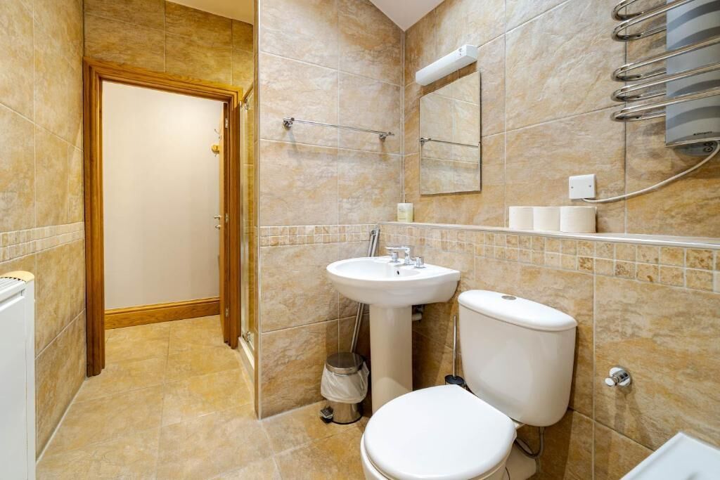A bathroom with a toilet, sink, and shower area.