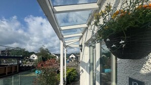 A covered outdoor area with a glass roof, a number '12' sign, and a hanging flower basket. - Waterhead Retreat (Ambleside)