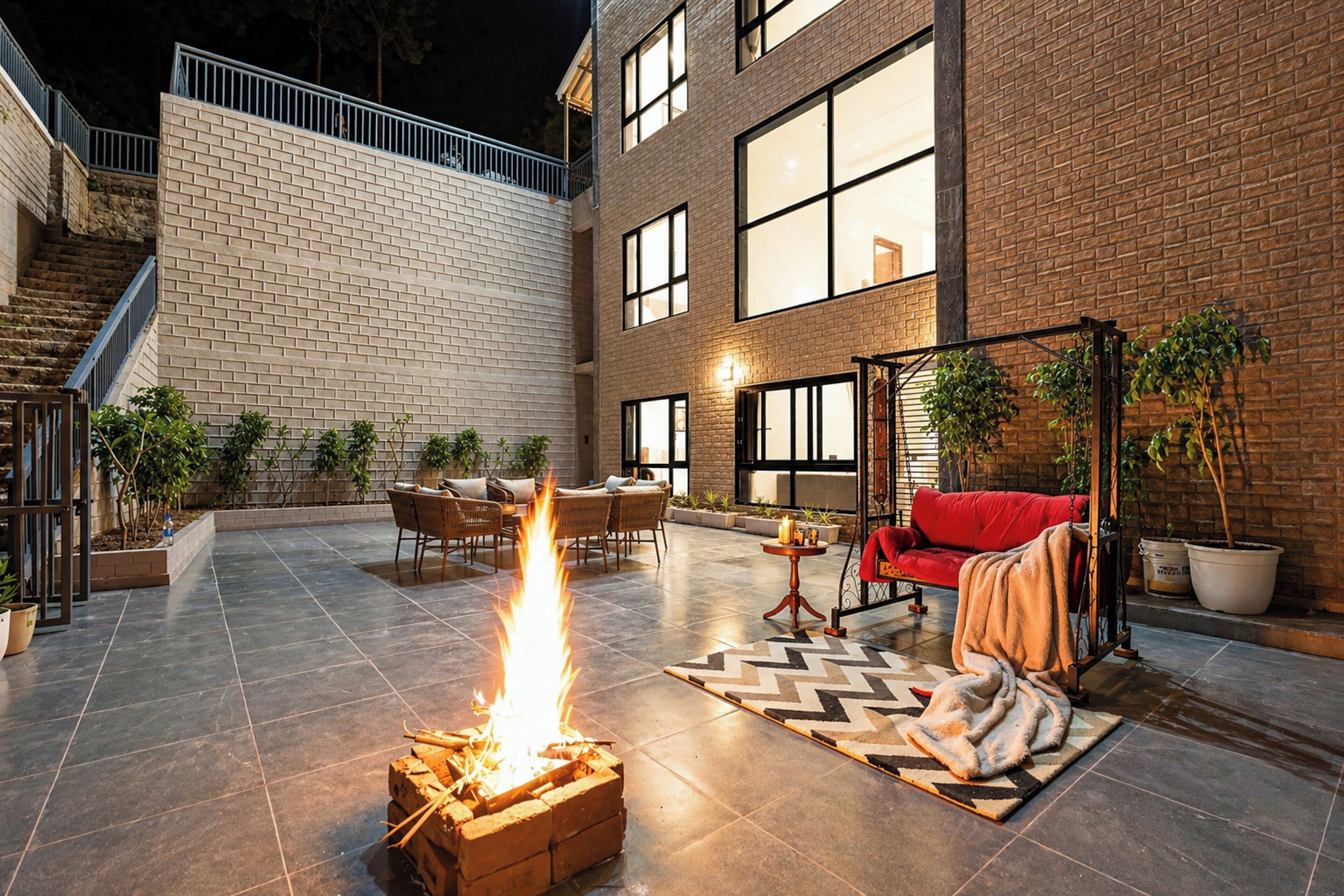 A courtyard with a fire pit, outdoor seating, and a staircase leading to an upper level.