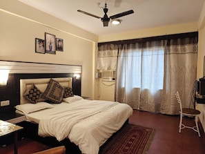 Un dormitorio con cama, escritorio, silla, ventilador de techo y cortinas.
