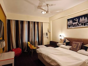 Habitación de hotel con cama, escritorio, silla, televisión y un cuadro en la pared.