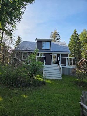 Une maison avec un toit en métal, une petite terrasse et un escalier menant à la porte d’entrée.