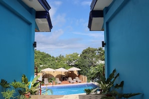 A pool area with lounge chairs and umbrellas, surrounded by blue walls and potted plants.