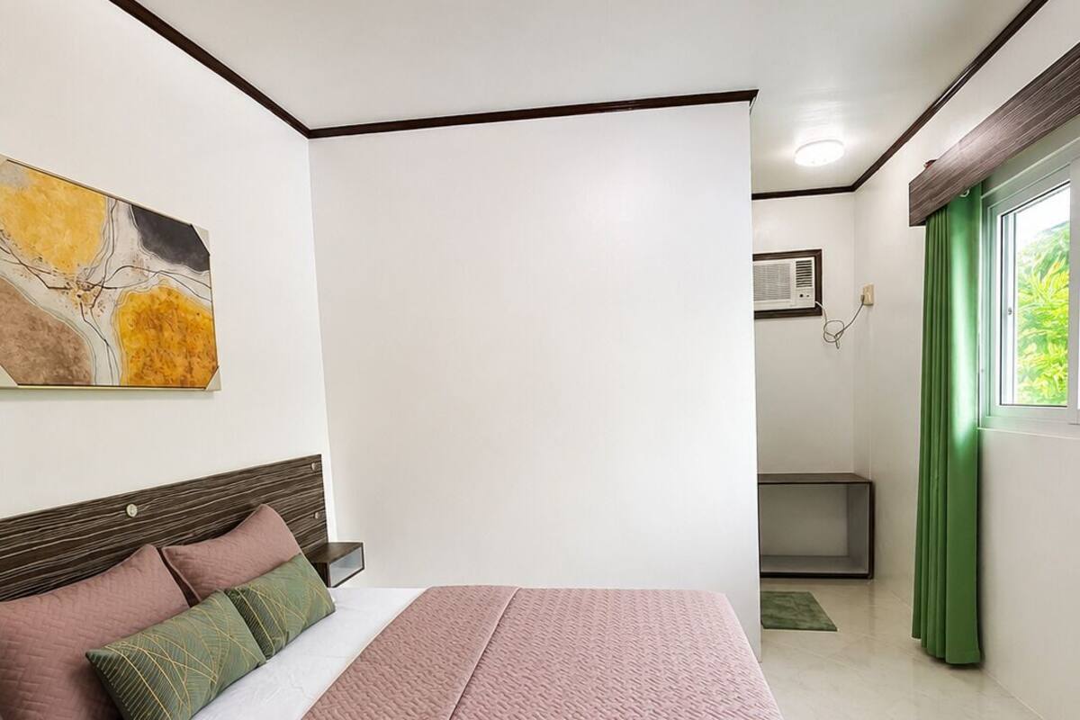 A modern bedroom with a bed, a wall-mounted air conditioning unit, and a window with curtains.