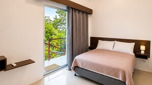 A modern bedroom with a bed, bedside table, and a view of greenery outside. - Mi Corazón Resort (Mabini)