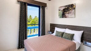 A modern hotel room with a large bed, a nightstand, a painting, and a view of the outdoors. - Mi Corazón Resort (Mabini)