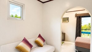 A bedroom with a bed, a window, and an arched doorway leading to another room. - Mi Corazón Resort (Mabini)