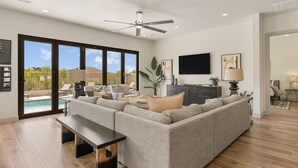 A spacious living room with a sectional sofa, a flat-screen TV, and a ceiling fan. - Golf Course Views 8 Bedroom Townhouse (Washington)