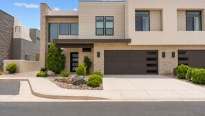 A modern two-story house with a garage, a stone facade, and a landscaped front yard. - Golf Course Views 8 Bedroom Townhouse (Washington)