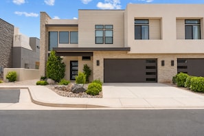 A modern two-story house with a garage, a stone facade, and a landscaped front yard. - Golf Course Views 8 Bedroom Townhouse (Washington)