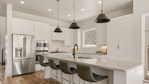 A modern kitchen with a central island, stainless steel appliances, and bar stools. - Golf Course Views 8 Bedroom Townhouse (Washington)