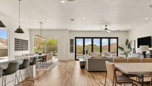 A modern kitchen with a bar area, dining space, and a large window with a view of the desert. - Golf Course Views 8 Bedroom Townhouse (Washington)