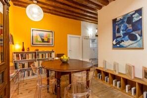 Ein Essbereich mit einem Holztisch, Stühlen, einem Bücherregal und einem Gemälde an der Wand.