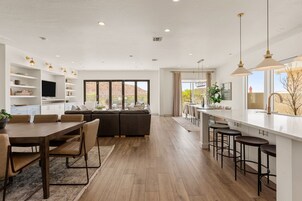 A spacious kitchen with a dining area, a living room with a sofa, and a bar area with stools.
