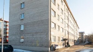 Monikerroksinen rakennus, jossa on tiiliverhous, tasakatto ja katutasossa sijaitseva sisäänkäynti.