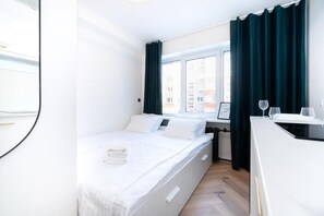 A modern hotel room with a bed, a desk, and a window with curtains. - Tallinn Airport Studios by RevalHome (Tallinn)