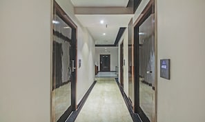 A hotel hallway with a marble floor, wooden doors, and a digital display showing room number 402. - Dee Empresa Hotel (Kolkata)