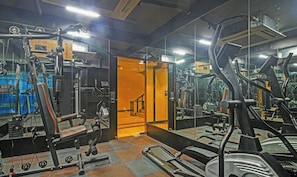 A gym with exercise equipment, mirrors, and a mirrored wall.