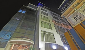 A multi-story hotel with a glass facade, a sign reading 'Dee Empresa Hotel,' and a visible entrance.