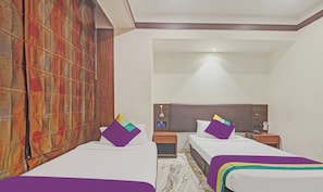 A hotel room with two beds, a wooden headboard, a nightstand, and a curtain.