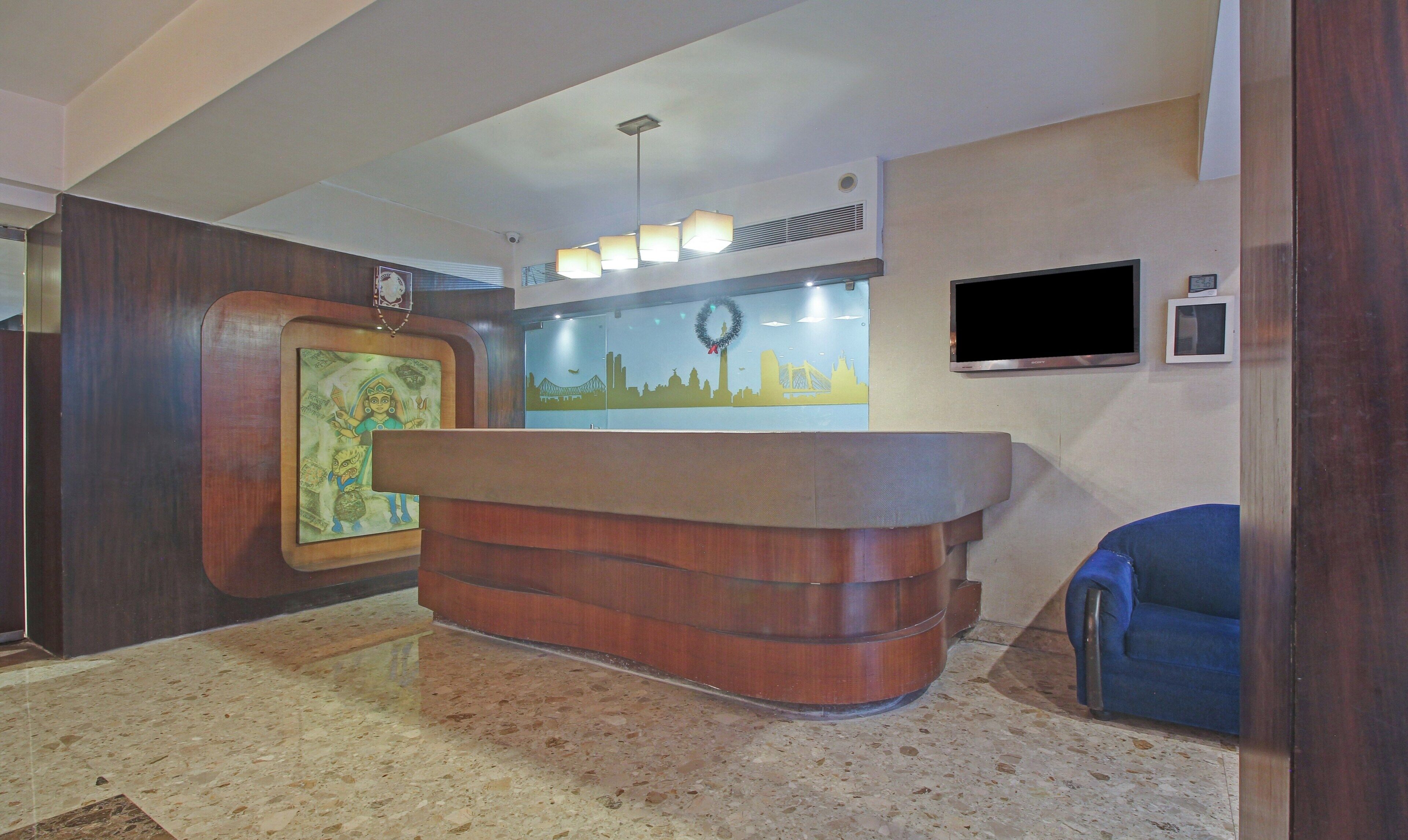 A reception desk with a wooden finish, a wall-mounted flat-screen TV, and a framed picture on the wall.