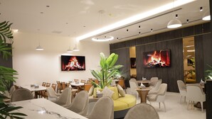 A modern dining area with marble tables, comfortable seating, and a large plant centerpiece. - ISHQ Hotel (Aqaba)