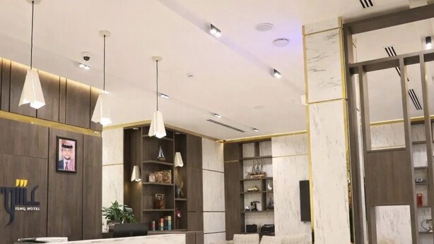 A hotel reception area with a marble counter, pendant lighting, a sofa, and a seating area with armchairs. - ISHQ Hotel (Aqaba)