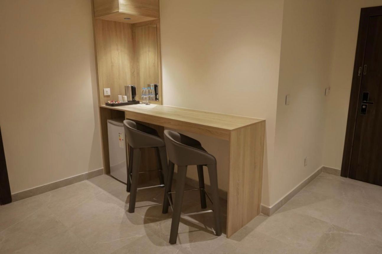 Eine kleine Küchenzeile mit einer Holz Arbeitsplatte, zwei Barhocker und einem Kühlschrank.